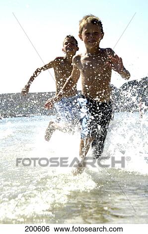 Two boys playing in water on beach View Large Photo Image Stock Photograph - Two boys playing in water on beach . Fotosearch