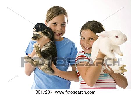 Stock Photo - Two girls holding rabbits, Studio Shot . Fotosearch