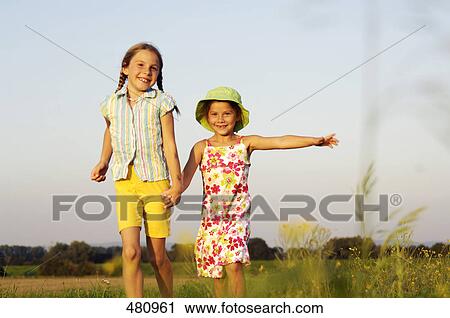 Stock Image - Two girls walking in field . Fotosearch