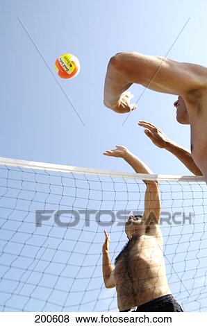 Stock Photo - Two men playing volleyball on beach . Fotosearch