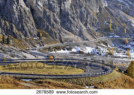 Stock Photo - Two mountain bikers cycling through curved road, Trentino Alto Adige, Dolomites, Italy . Fotosearch