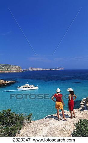 Stock Photo - Two people standing on cliff, Cala Comte, Ibiza, Balearic Islands, Spain . Fotosearch