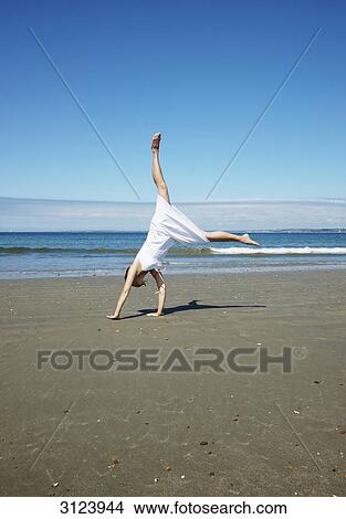 Woman doing a cartwheel on the beach View Large Photo Image Picture - Woman doing a cartwheel on the beach . Fotosearch