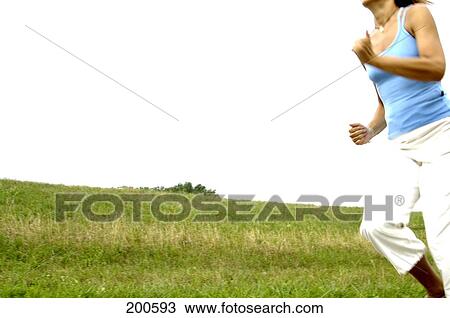 Stock Image - Woman jogging in field . Fotosearch