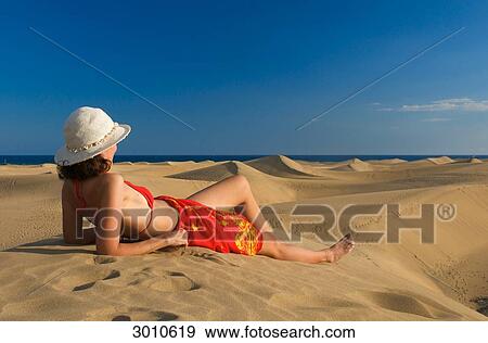 Woman lying on a sand dune looking at the sea, Maspalomas, Gran Canaria, Spain, side view View Large Photo Image Stock Photo - Woman lying on a sand dune looking at the sea, Maspalomas, Gran Canaria, Spain, side view . Fotosearch