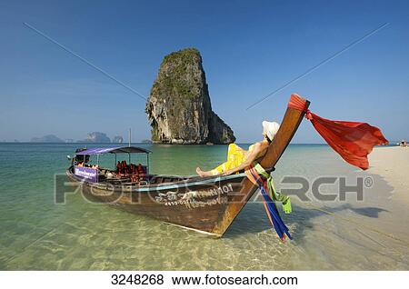 Stock Photo - Woman lying on longtail boat, Laem Phra Nang Beach, Krabi, Thailand . Fotosearch