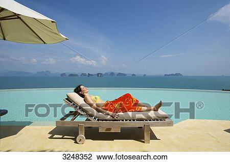 Stock Image - Woman lying on sunlounger, Evason Six Senses Hideaway, Yao Noi, Thailand . Fotosearch