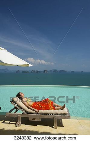 Stock Image - Woman lying on sunlounger, Evason Six Senses Hideaway, Yao Noi, Thailand . Fotosearch