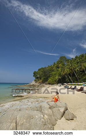 Stock Photo - Woman sitting at beach, Surin Beach, Phuket, Thailand . Fotosearch