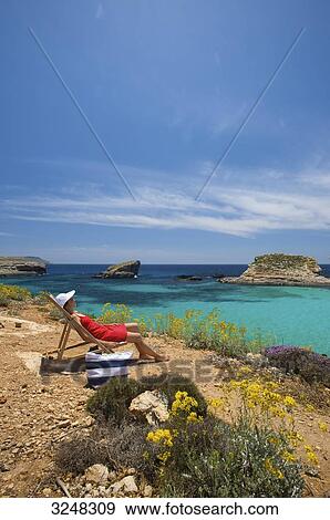Woman sitting in sunlounger, Blue lagoon, Comino, Malta View Large Photo Image Stock Photo - Woman sitting in sunlounger, Blue lagoon, Comino, Malta . Fotosearch
