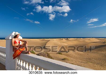 Woman sitting on a fence looking at the sand dunes, Maspalomas, Gran Canaria, Spain View Large Photo Image Stock Photography - Woman sitting on a fence looking at the sand dunes, Maspalomas, Gran Canaria, Spain . Fotosearch