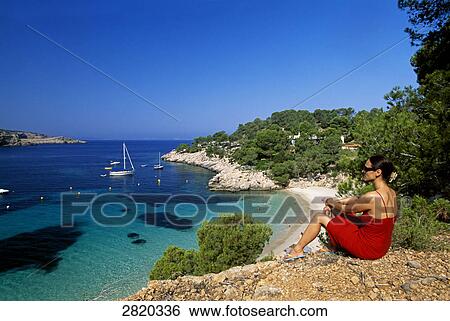 Woman sitting on cliff, Cala Salada, Ibiza, Balearic Islands, Spain View Large Photo Image Stock Photograph - Woman sitting on cliff, Cala Salada, Ibiza, Balearic Islands, Spain . Fotosearch