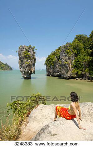 Stock Image - Woman sitting on rock, Phang-Nga, Thailand . Fotosearch