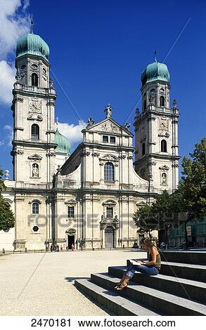 Stock Image - Woman sitting on steps in front of cathedral, St. Stephan's Cathedral, Passau, Lower Bavaria, Bavaria, Germany . Fotosearch