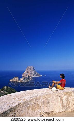 Woman sitting on tower, Es Vedra, Ibiza, Balearic Islands, Spain View Large Photo Image Stock Photography - Woman sitting on tower, Es Vedra, Ibiza, Balearic Islands, Spain . Fotosearch