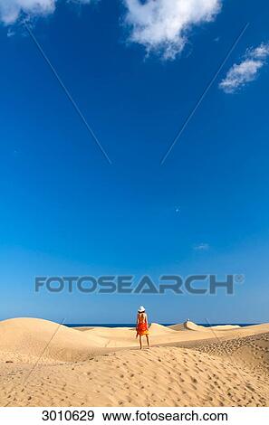 Stock Photo - Woman standing on a sand dune, Maspalomas, Gran Canaria, Spain, rear view . Fotosearch