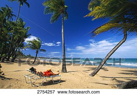 Stock Photo - Woman sunbathing on beach, Coco Beach, Puerto Rico . Fotosearch