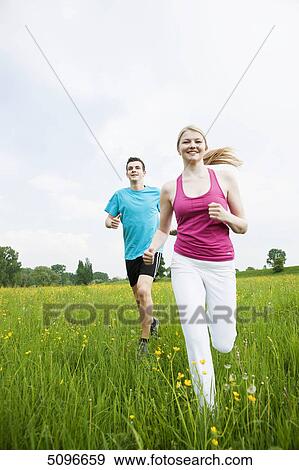 Stock Photo - Young couple running in meadow . Fotosearch