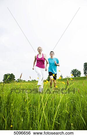 Young couple running in meadow View Large Photo Image Stock Photograph - Young couple running in meadow . Fotosearch