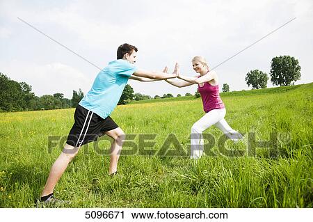 Stock Image - Young couple stretching in meadow . Fotosearch