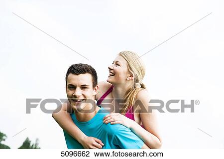 Stock Image - Young man carrying girlfriend piggyback . Fotosearch