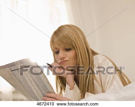 Young woman lying with newspaper in bed View Large Photo Image Stock Image - Young woman lying with newspaper in bed . Fotosearch