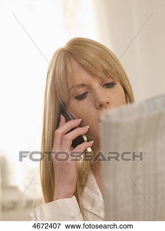 Stock Photo - Young woman lying with newspaper in bed . Fotosearch