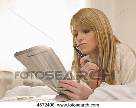 Young woman lying with newspaper in bed View Large Photo Image Stock Photo - Young woman lying with newspaper in bed . Fotosearch