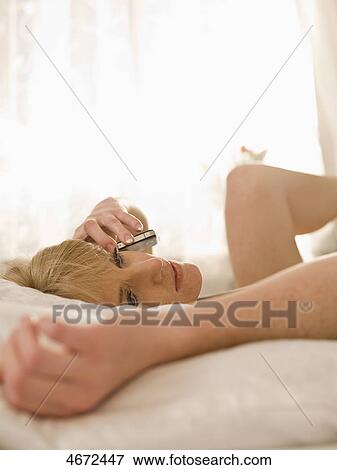 Stock Photo - Young woman phoning in bed . Fotosearch