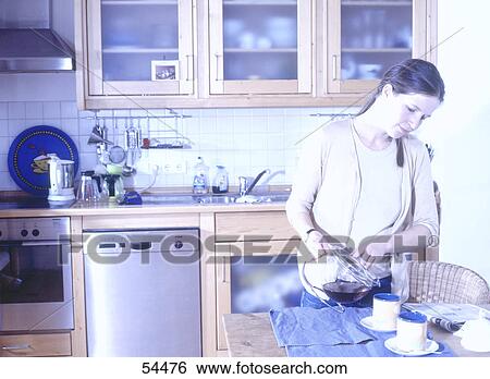 Stock Photograph - Young woman preparing breakfast in kitchen . Fotosearch