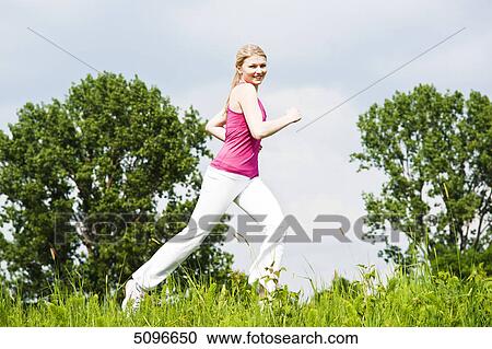 Stock Image - Young woman running in meadow . Fotosearch