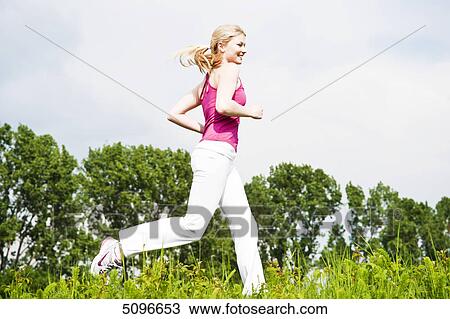 Stock Image - Young woman running in meadow . Fotosearch