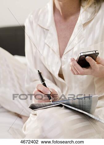 Stock Image - Young woman sitting in bed . Fotosearch