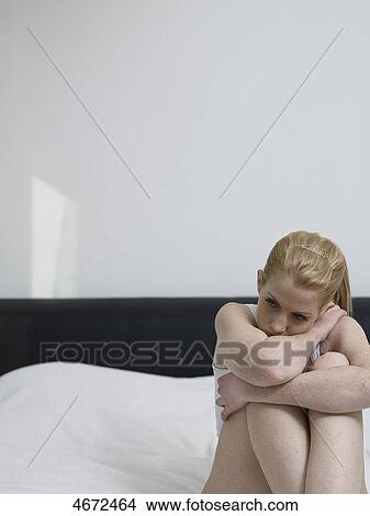 Picture - Young woman sitting on bed . Fotosearch