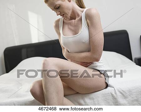 Stock Photo - Young woman sitting on bed . Fotosearch