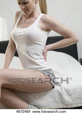 Stock Photo - Young woman sitting on bed . Fotosearch