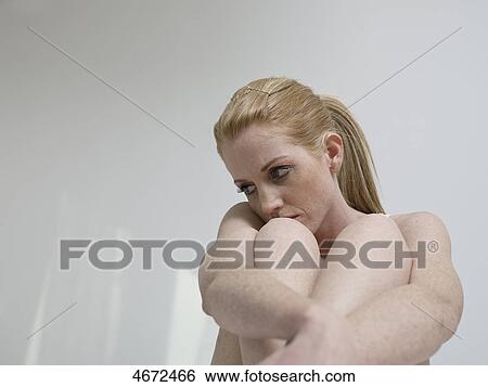 Stock Photograph - Young woman sitting on bed . Fotosearch