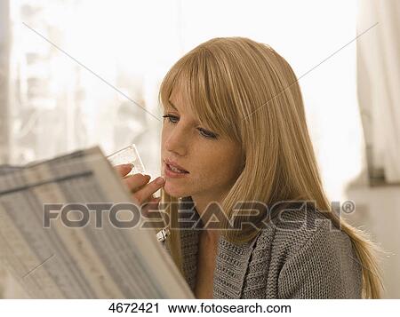 Stock Image - Young woman with newspaper in bed . Fotosearch