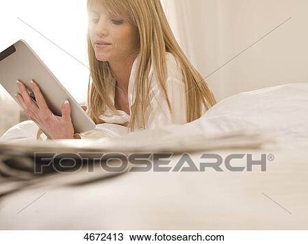Stock Image - Young woman with Tablet PC in bed . Fotosearch