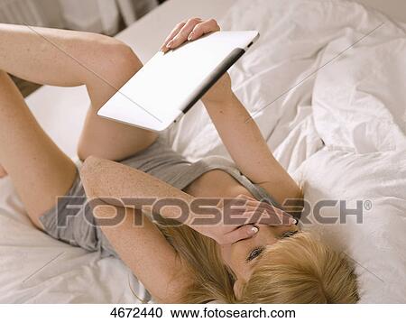 Stock Image - Young woman with Tablet PC in bed . Fotosearch