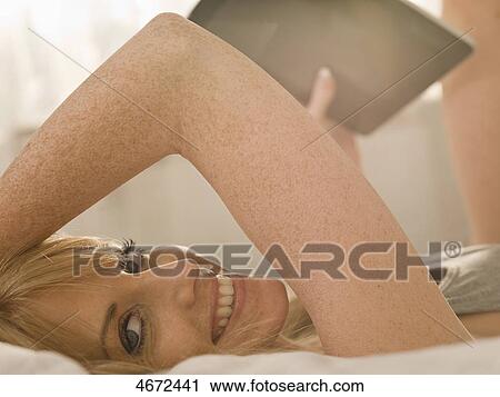 Stock Image - Young woman with Tablet PC in bed . Fotosearch