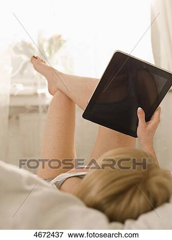 Stock Photo - Young woman with Tablet PC in bed . Fotosearch