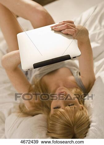 Stock Photo - Young woman with Tablet PC in bed . Fotosearch