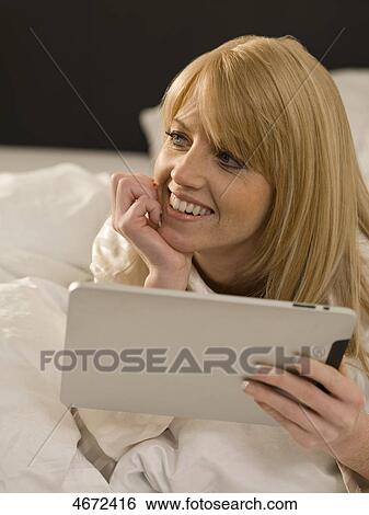 Stock Photograph - Young woman with Tablet PC in bed . Fotosearch