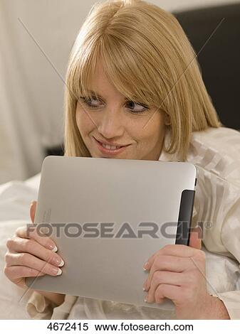 Stock Photography - Young woman with Tablet PC in bed . Fotosearch