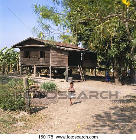 Boy standing in front of a wooden house, Thailand View Large Photo Image Stock Photo - Boy standing in front of a wooden house, Thailand . Fotosearch
