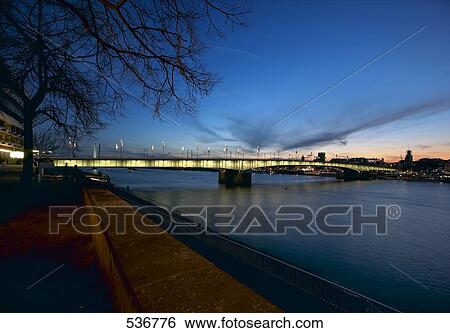 Stock Photograph - Bridge across river lit up at night, Cologne, Germany . Fotosearch