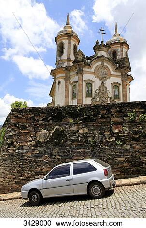 Stock Image - Car in front of a wall, Sao Francisco church in the background, Ouro Preto, Minas Gerais, Brazil . Fotosearch