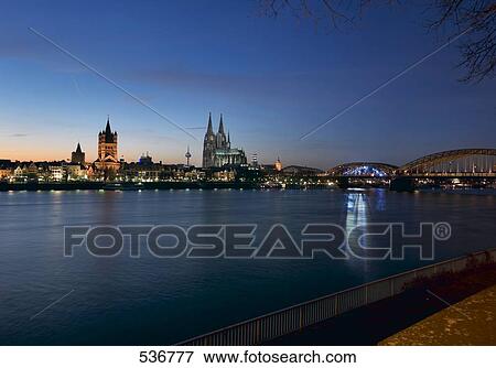 Stock Photo - City at waterfront lit up at night . Fotosearch