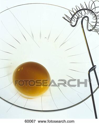 Stock Photo - Close-up of egg yolk and wire whisk in bowl . Fotosearch